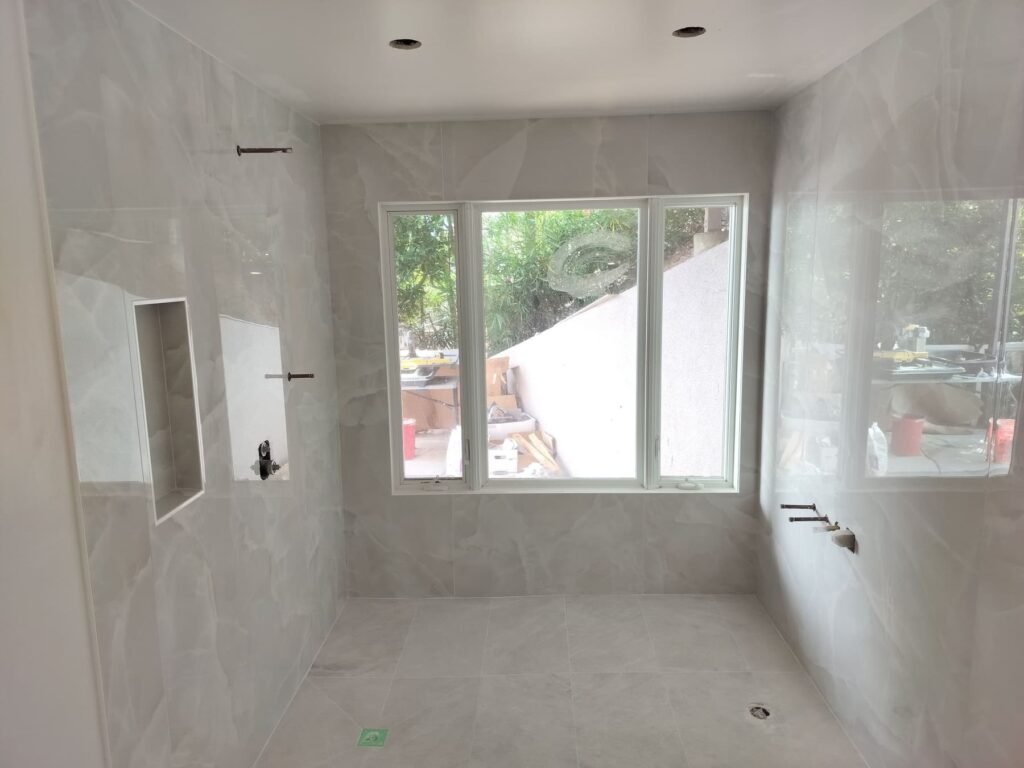After: Sugarloaf master bath in large-format porcelain with mitred niche