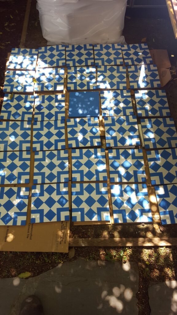 Blue-and-white geometric tiles arranged outdoors with a solid blue accent tile for the Mill Valley bathroom project.