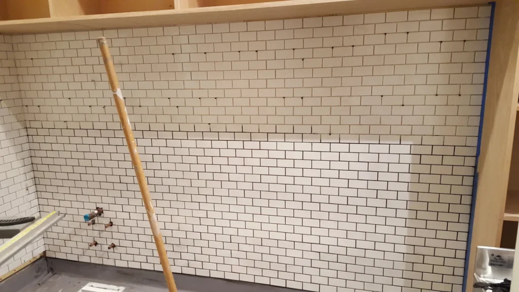 Close-up of white subway tile installation beneath wood cabinetry at Fiorella Restaurant in San Francisco.