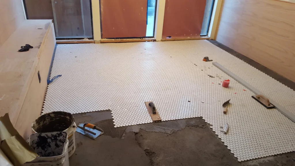 White hexagon mosaic floor tiles being installed over combed thinset mortar at Fiorella Restaurant in San Francisco.