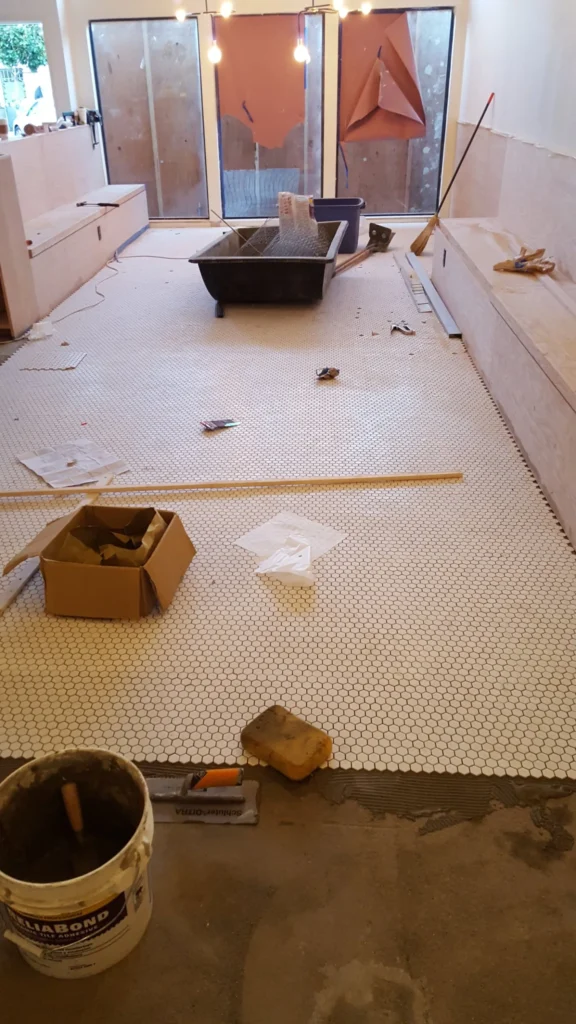 Large area of white hexagon mosaic flooring being installed inside Fiorella Restaurant in San Francisco.