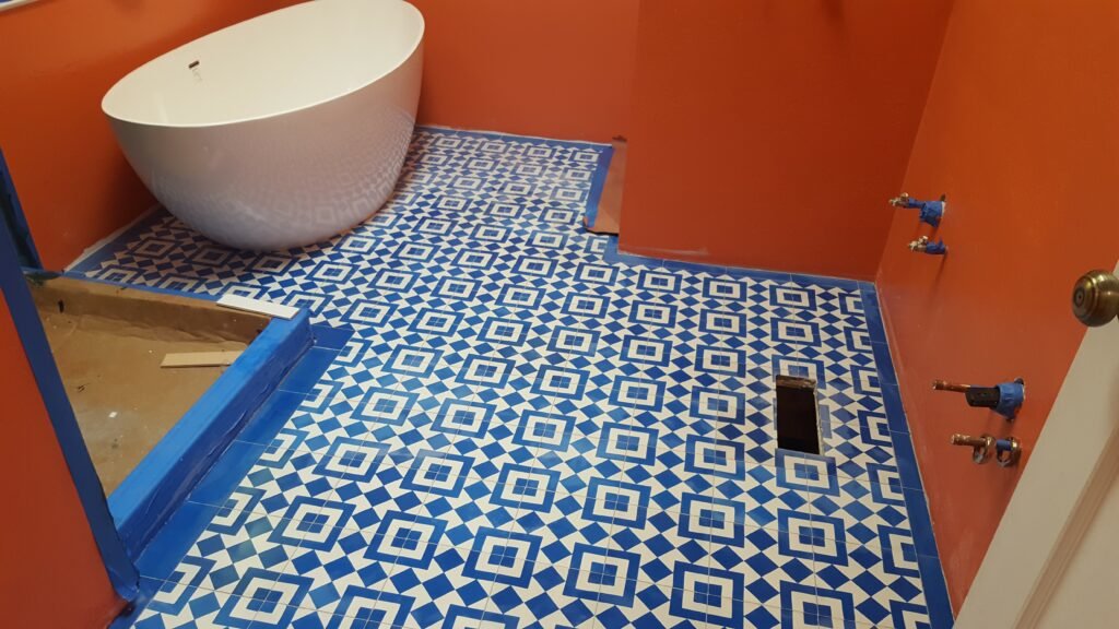 Installed blue-and-white geometric tile floor beside a freestanding tub and taped shower base in a Mill Valley bathroom.