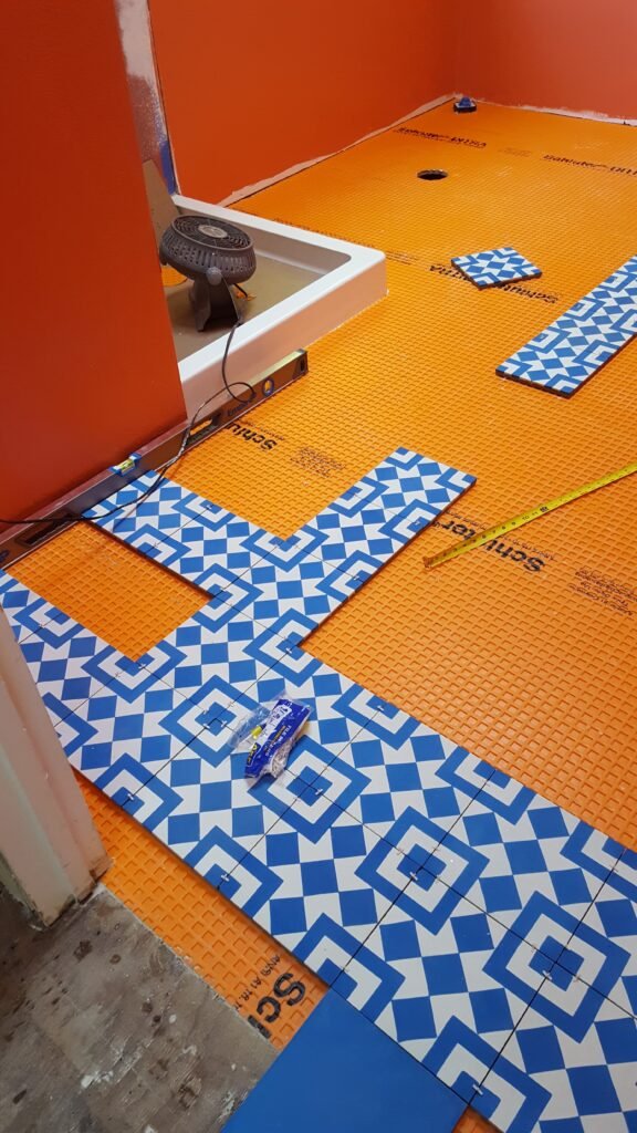 Blue-and-white patterned floor tiles laid out on Schluter-DITRA beside a new shower base in a Mill Valley bathroom remodel.